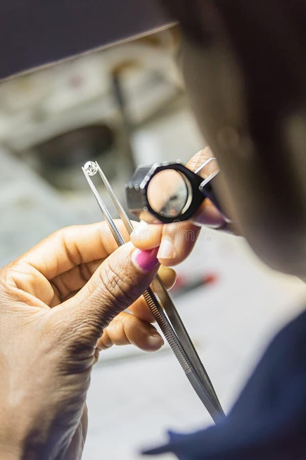 Jeweler looking a diamond through a magnifying glass.